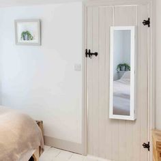 a bedroom with a bed and mirror on the wall next to it's door