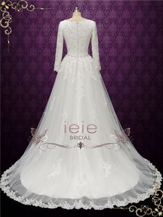 a white wedding dress with long sleeves and lace on the skirt is displayed in front of a purple background