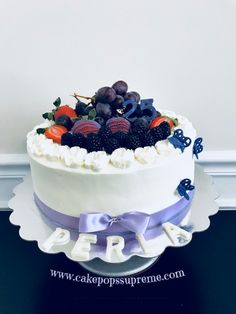 a white cake topped with berries and blue ribbon