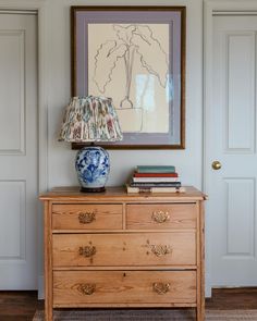 a blue and white vase sitting on top of a wooden dresser next to a lamp