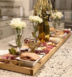 an assortment of food is displayed on a long table in a kitchen with white flowers