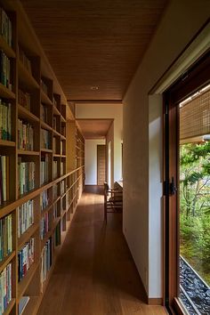 a long hallway with bookshelves full of books on the walls and wooden floors