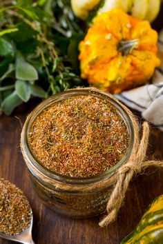 a glass jar filled with seasoning next to other spices and herbs on a wooden table