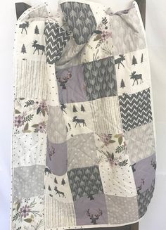 a quilted blanket with deers and trees on it, sitting on a chair