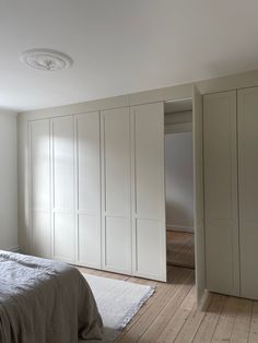 a bedroom with white closets and wooden floors