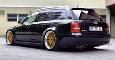 an audi wagon with gold rims parked in front of a building