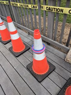 three orange and white cones sitting on top of a wooden deck next to caution tape