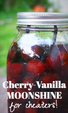 a jar filled with cherries sitting on top of a wooden table