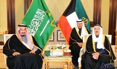 two men sitting next to each other in front of flags and chairs with one man wearing a headscarf