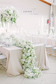 the table is set up with white flowers and greenery for an elegant wedding reception