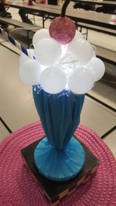 a blue vase with white and red balloons in it on a pink tableclothed place mat