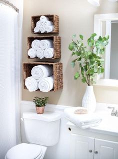 a white toilet sitting next to a bathroom sink under a window with towels on it