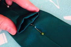 someone is sewing something on top of a piece of green fabric with pins in it