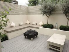 an outdoor seating area with benches and trees in the back ground, surrounded by shrubbery