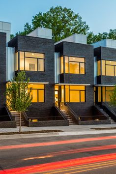 a row of black brick townhouses with stairs leading up to the upper floor windows