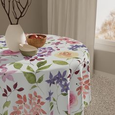 a table with a bowl of fruit on it next to a vase filled with flowers