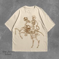 1x Vintage Cowbow Skeleton T-Shirt Our shirts come in unisex sizing and are produced from the finest quality materials, making them incredibly soft and cozy! The high-quality print on our T-shirt features beautiful colors and detailing, ensuring the design stands out beautifully against the fabric. The print is durable, resistant to fading, and offers a long-lasting, premium look and feel. Size - True to size (Comfort fit) - Sizes from small to 5XL - For an oversized fit, size up 1-2 sizes from your normal size - Unisex fit (Looser fit for women) Designs Different colors available, see pictures for references. Made using 100% US cotton that is ethically grown and harvested.  Care Instructions Machine wash: cold (max 30C or 90F). Do not bleach, tumble dry or dry clean. Do not iron directly Skeleton T Shirt, 90s Shirts, Cowboys Shirt, Cow Boy, Retro 90s, Unisex Shirt, Skeleton, Beautiful Colors, Comfort Fit