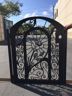 an iron gate with flowers and leaves on it in the middle of a parking lot