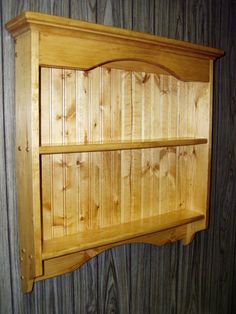 a wooden shelf on the side of a wall next to a wood paneled wall