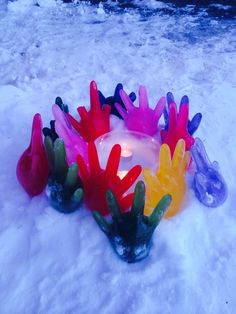 several plastic hand prints in the snow with a lit candle on it's side