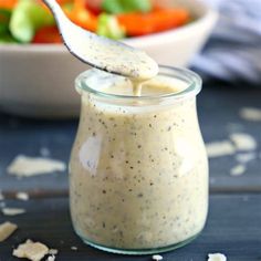 a spoon full of dressing next to a bowl of salad