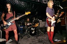 two women are playing guitars and singing on stage