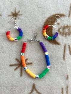 Radiate love and joy with this enchanting bracelet and earring set, adorned with vibrant rainbow colors and charming heart beads. This set is a celebration of positivity and happiness, beautifully crafted to add a pop of color to any outfit. Whether you're spreading love or simply brightening your day, this whimsical set is the perfect accessory to express your vibrant personality and embrace life's colorful moments. Everyday Heart-shaped Colorful Beads Jewelry, Adjustable Rainbow Heart Beads Jewelry, Rainbow Jewelry With Letter Beads For Gift, Rainbow Colored Jewelry With Letter Beads For Gift, Playful Heart Beads For Jewelry Making, Colorful Heart-shaped Round Beads Jewelry, Rainbow Heart Beads Jewelry For Gift, Rainbow Heart Beads Jewelry Gift, Playful Jewelry With Heart Beads