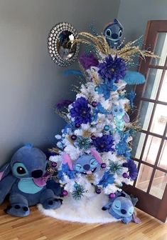 a blue and white christmas tree decorated with pooh, stitchers and other disney characters