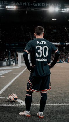 a soccer player is standing on the field with his back to the camera and looking at the ball