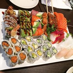 there are many sushi on the plate with chopsticks