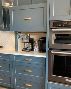 a kitchen with blue cabinets and stainless steel appliances in the center, along with an espresso machine on the counter