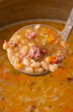 a spoon full of soup with ham and beans in it is being held by a ladle