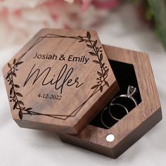 a wooden ring box with two wedding rings in it and the lid opened to show their names