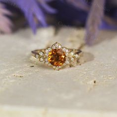 an orange and white diamond ring sitting on top of purple flowers