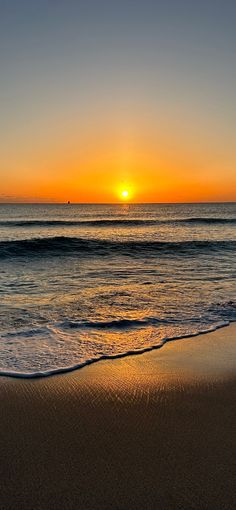 the sun is setting over the ocean with waves lapping in front of it,