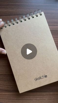 a hand holding a notebook with the word sketchie on it