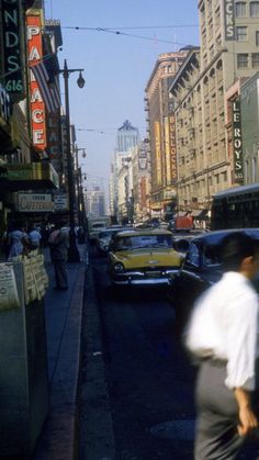 a busy city street with cars and people walking on the side walk near tall buildings