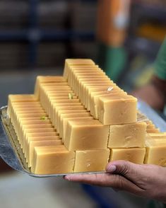 a person holding a metal tray filled with lots of yellow squares on top of each other