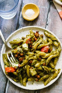 a white plate topped with pasta covered in pesto