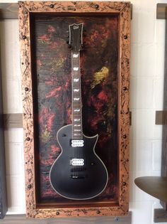 a black guitar is in a wooden frame