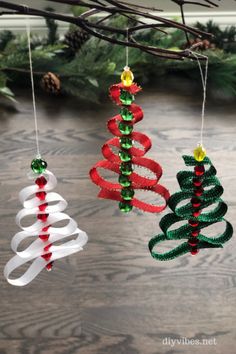 three christmas tree ornaments hanging from a branch