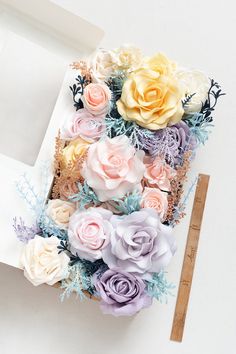 a bunch of flowers sitting on top of a white table next to a ruler and paper