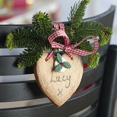 a wooden heart hanging from the back of a chair with holly and ivy on it