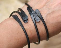 a woman's arm with three bracelets on it, one is black and the other is silver