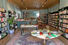 a room filled with lots of books on shelves next to a table full of books