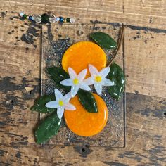 an orange decorated with flowers on top of a wooden table