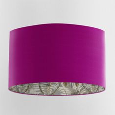 a purple lamp shade hanging from the ceiling with leaves printed on it and a white background