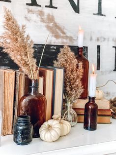 some books and vases are sitting on a mantle with candles in them, along with other decorative items