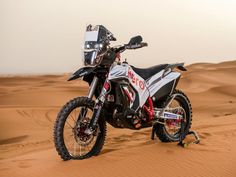 a dirt bike parked in the middle of sand dunes with no one around it,