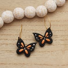 a pair of black and orange butterfly earrings sitting on top of a wooden table